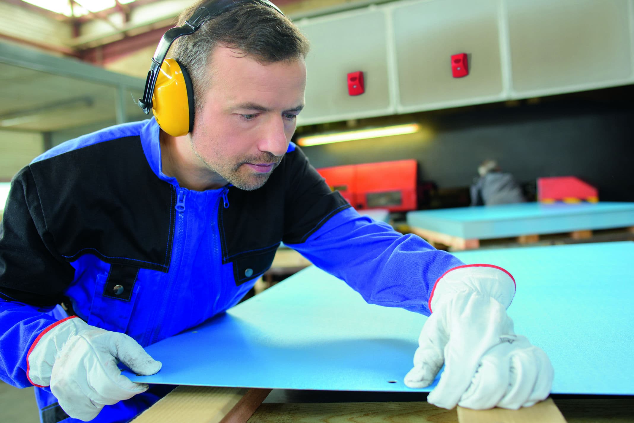 A factory worker in protective gear, examining a surface